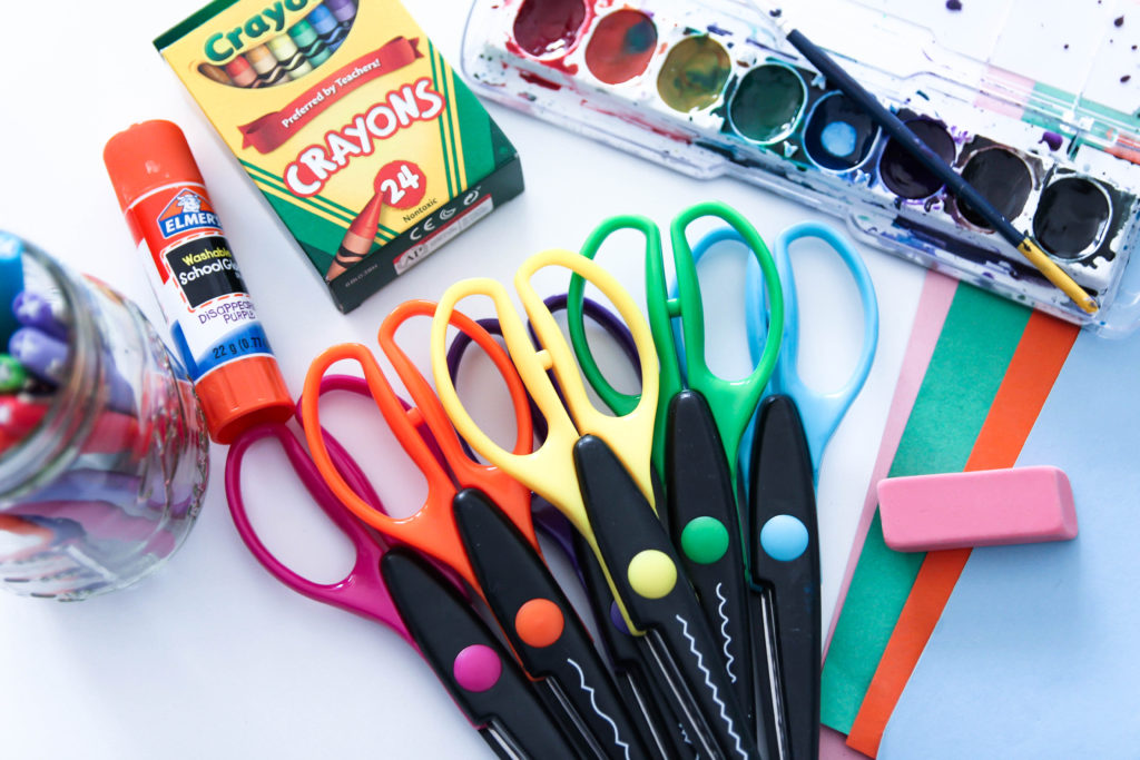This image shows art materials including scissors, watercolors, construction paper, glue, crayons, pens, erasers, and construction paper.